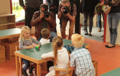 Vier Kinder sitzen in der Kita Kleine Robbeninsel an einem Tisch und werden von Pressefotografen fotografiert